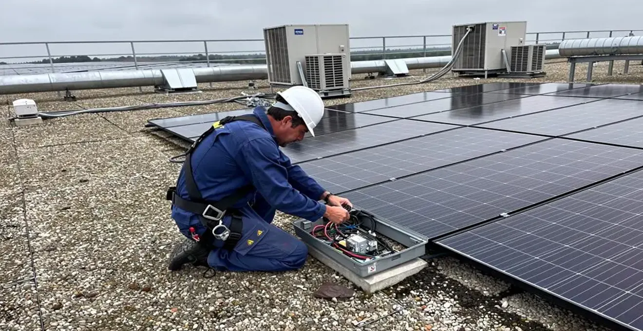 Technicien installant des panneaux photovoltaïques sur le toit d'un bâtiment professionnel en France.